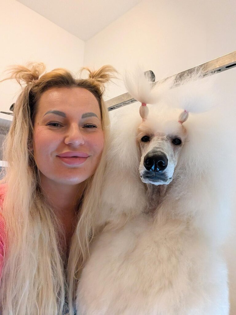 Lächelnde Züchterin im Selfie mit ihrem weißen Pudel